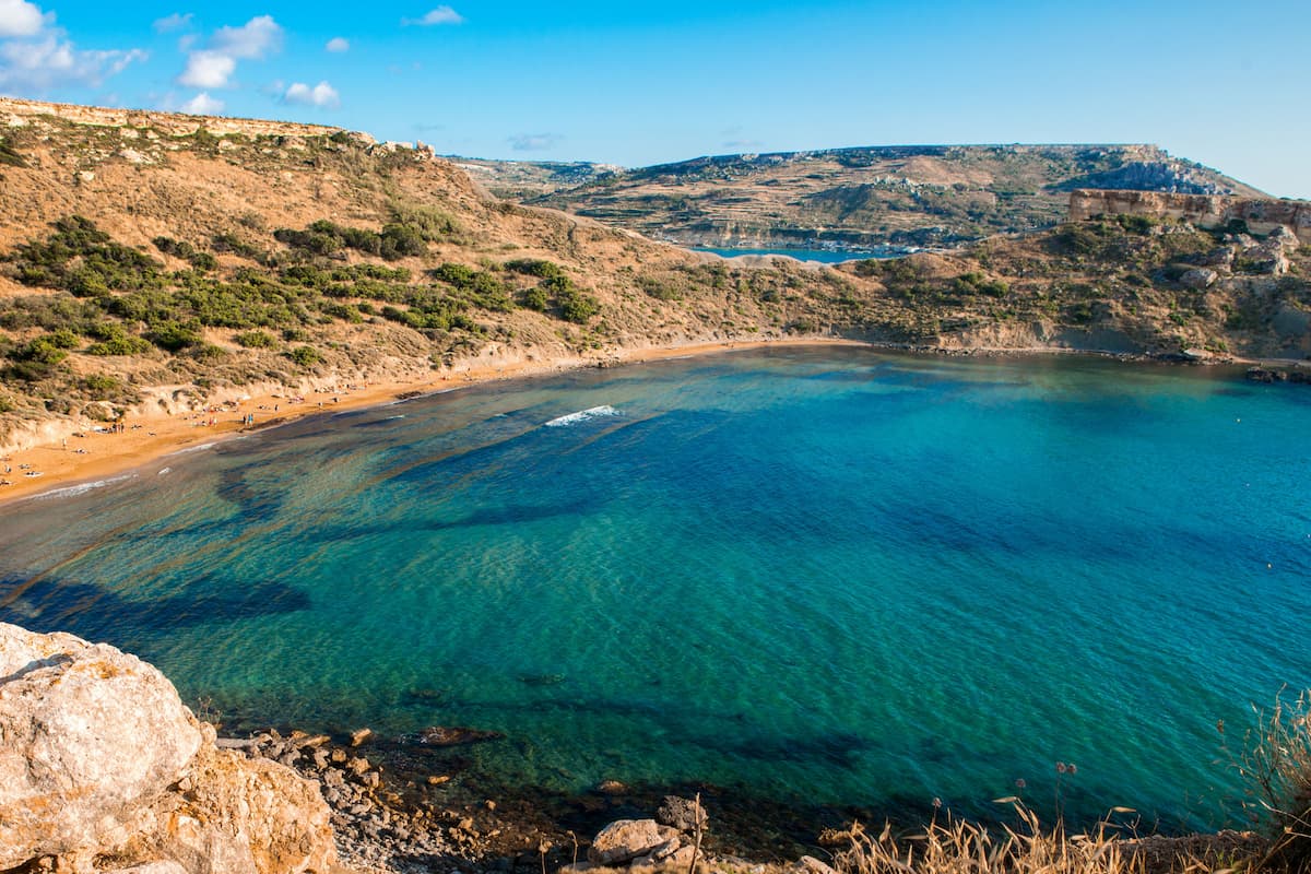 Turquoise bay with a golden sand beach framed by rocky hills in Malta