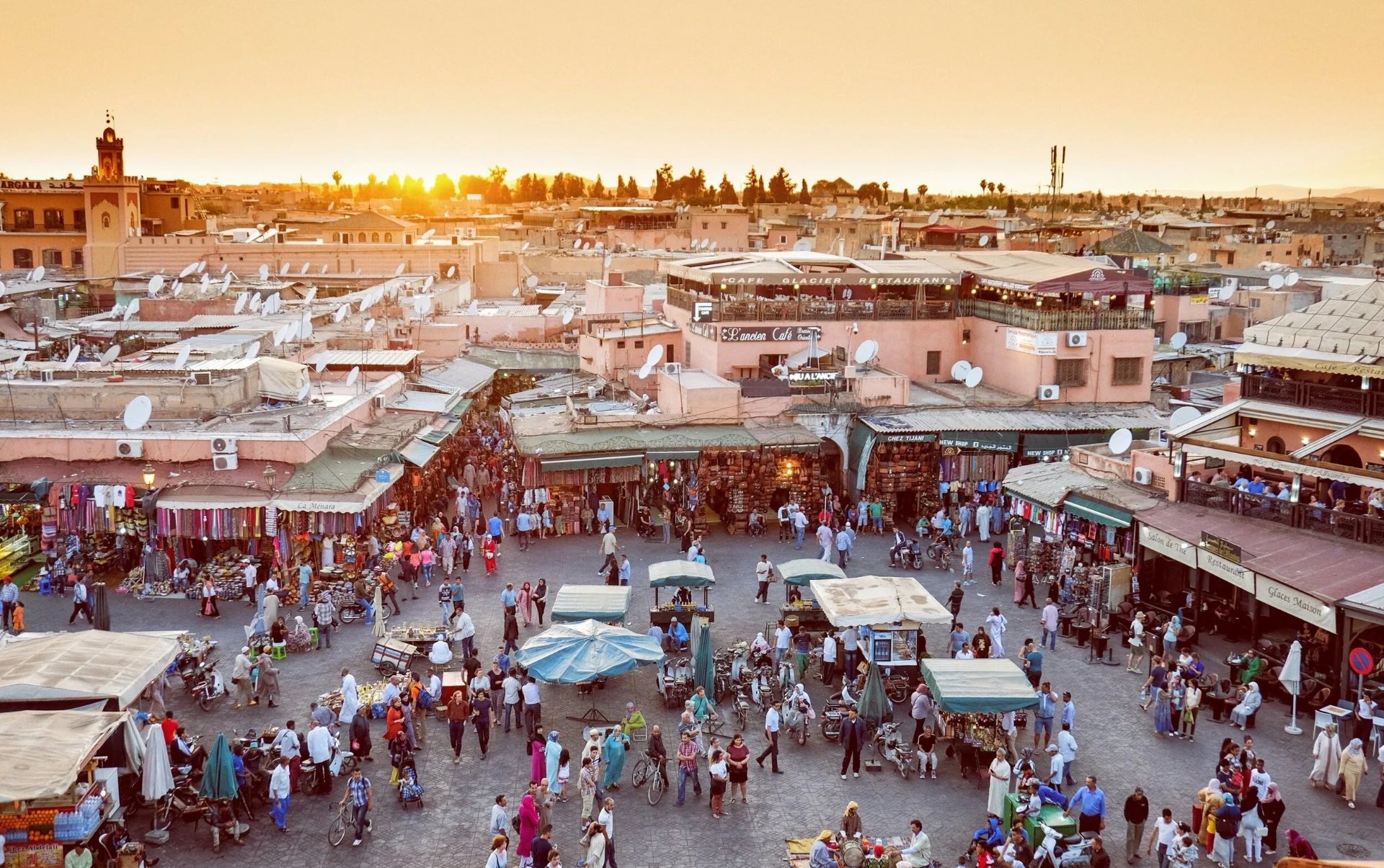Busy Marrakech market square and rooftops in warm sunset light