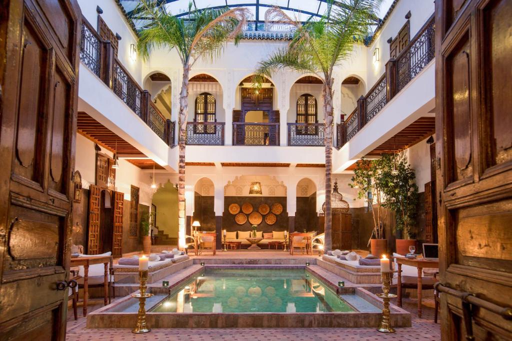 Marrakech riad courtyard with a pool, palms and carved wooden doors