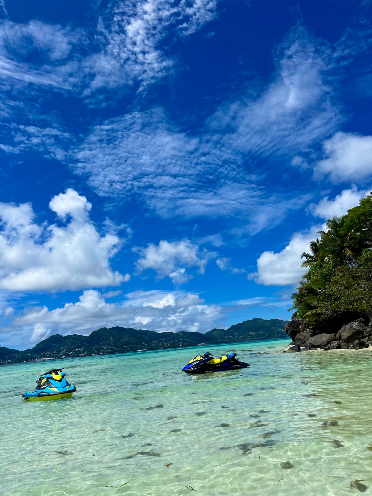 Turquoise water, jet skis and a rocky tropical shoreline in Seychelles